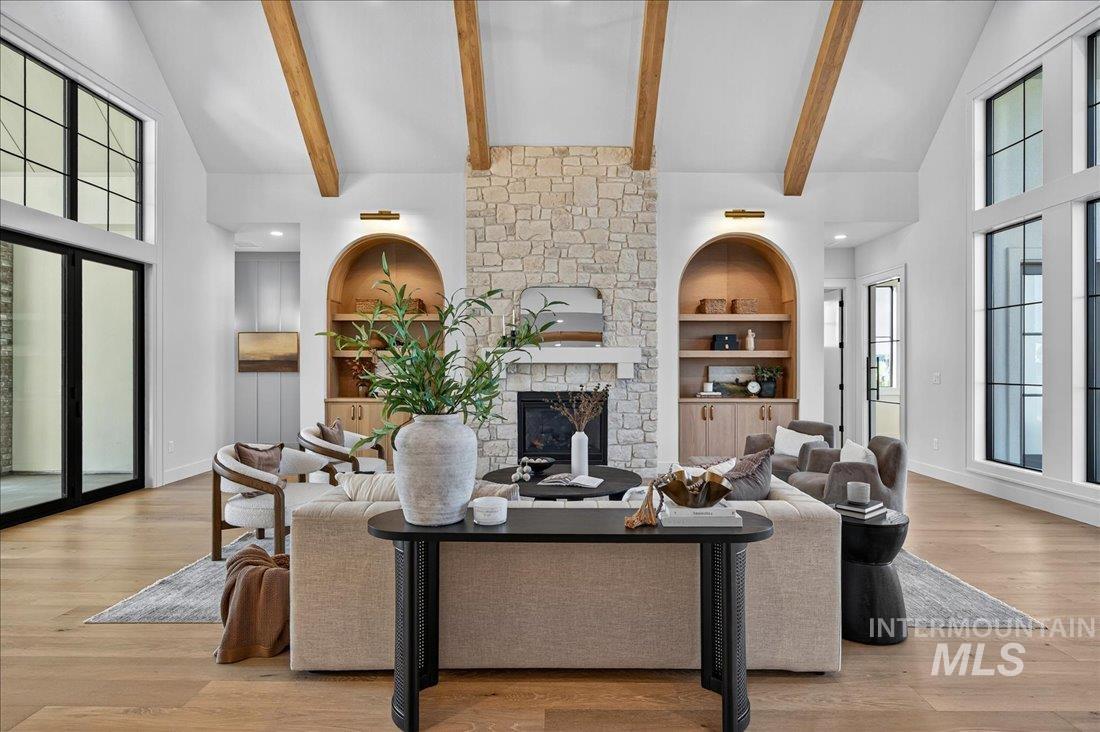Living room featuring high vaulted ceiling, built in shelves, a fireplace, light wood-type flooring, and beamed ceiling