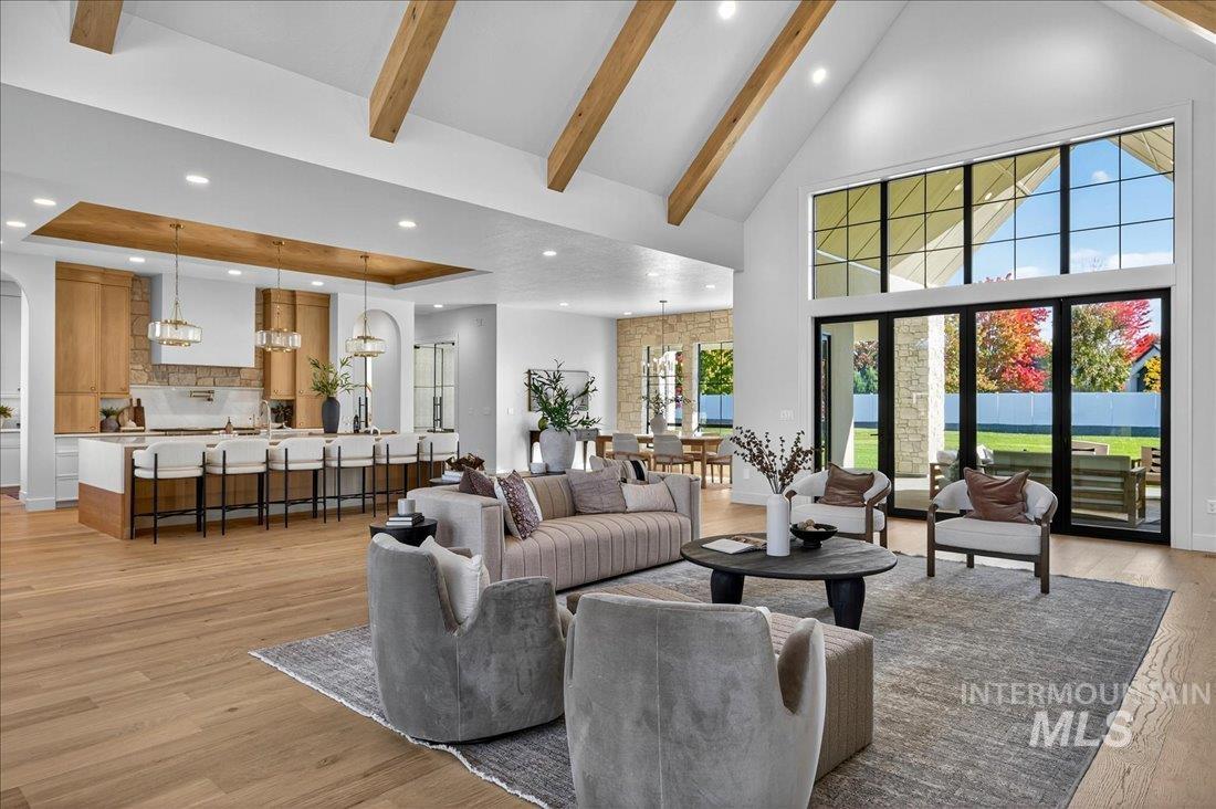 Living area with high vaulted ceiling, beamed ceiling, recessed lighting, and light wood-style flooring