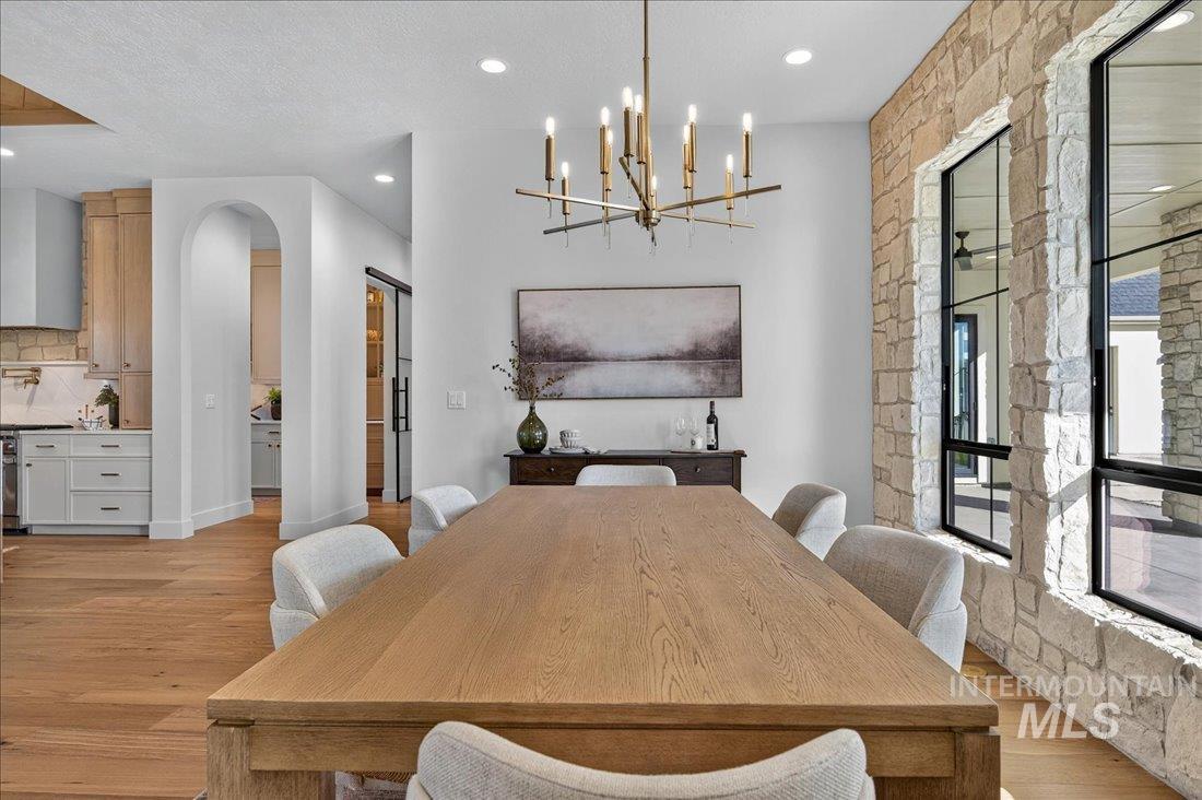 Dining area with light wood-style flooring, arched walkways, recessed lighting, and a chandelier