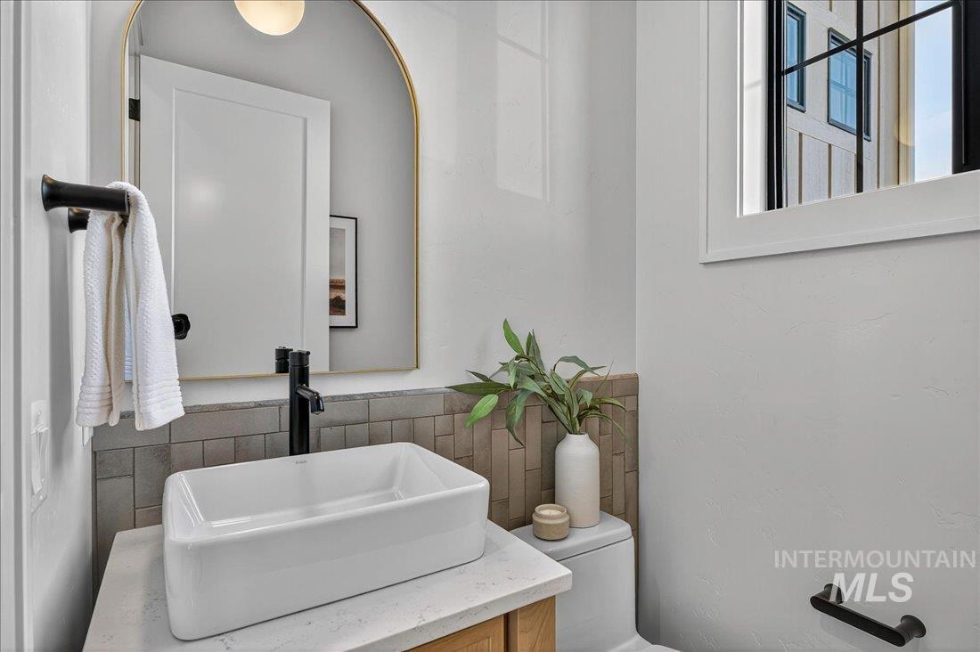 Half bathroom with vanity, tasteful backsplash, and tile walls