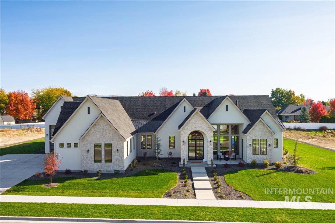 View of front of home featuring stone siding, a front yard, french doors, and stucco siding