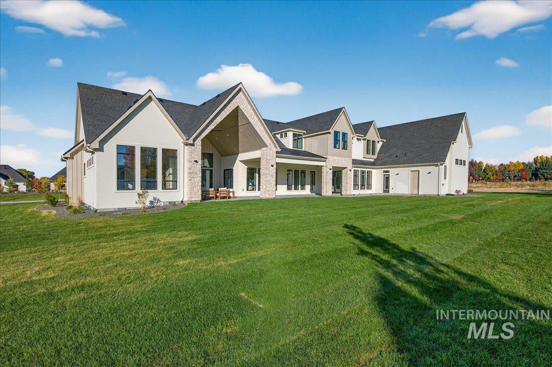 Rear view of property with a yard, a patio area, and stone siding