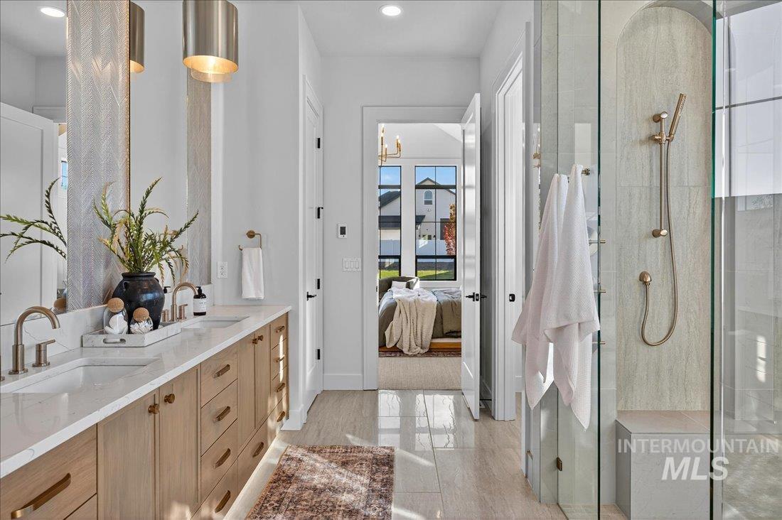 Bathroom with double vanity, a tile shower, connected bathroom, a chandelier, and light tile patterned floors