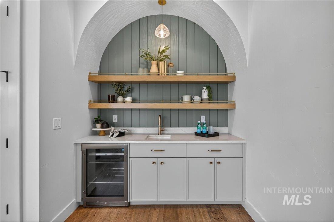 Bar featuring open shelves, wine cooler, white cabinets, and light stone counters