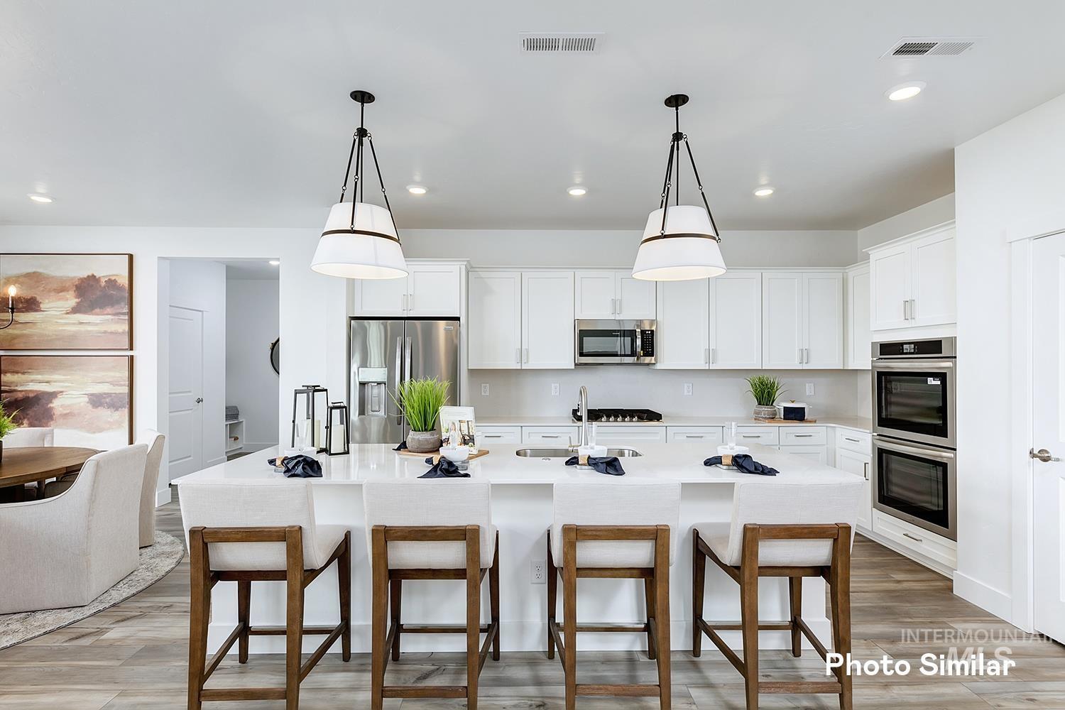 Kitchen featuring a breakfast bar, light wood finished floors, decorative light fixtures, white cabinets, and recessed lighting