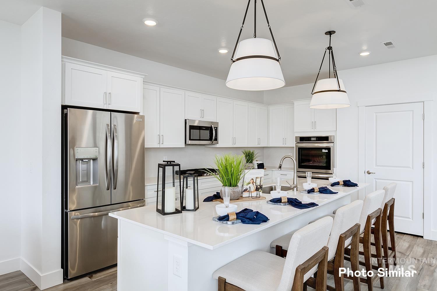 Kitchen with stainless steel appliances, light wood finished floors, white cabinets, a kitchen bar, and recessed lighting