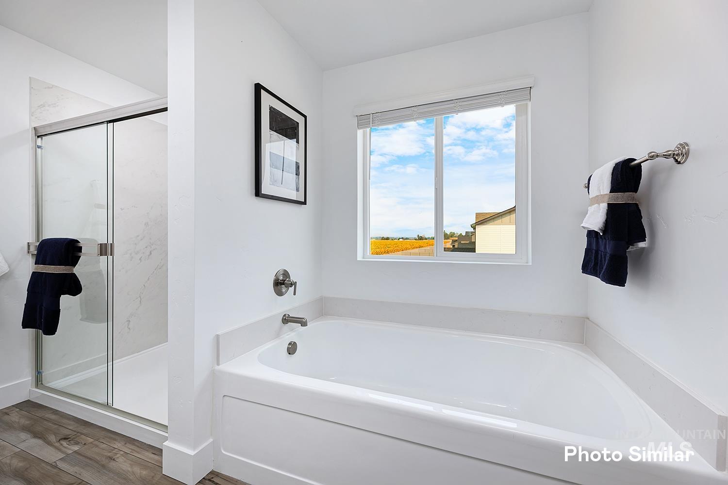 Bathroom with a bath, a marble finish shower, and wood finished floors