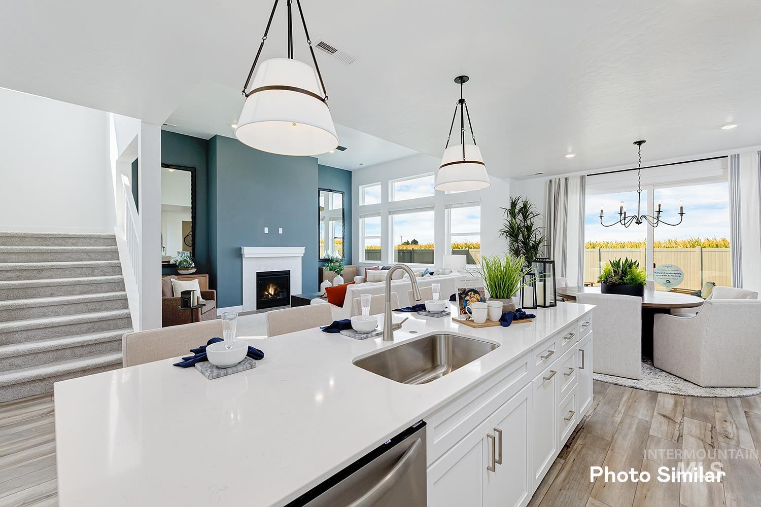 Kitchen featuring open floor plan, white cabinetry, light wood-style flooring, a chandelier, and a lit fireplace