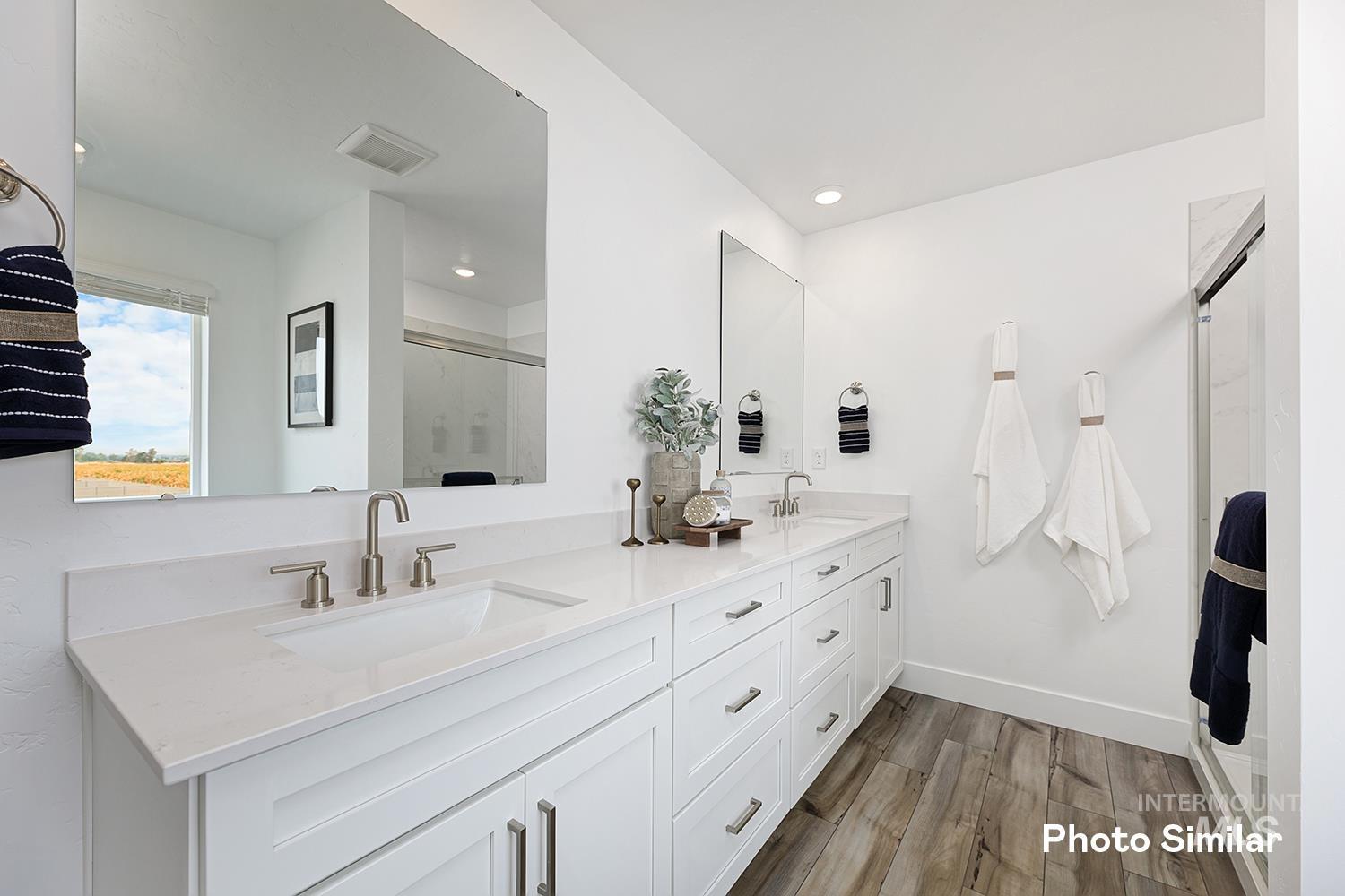 Bathroom with double vanity, a stall shower, and dark wood-style floors