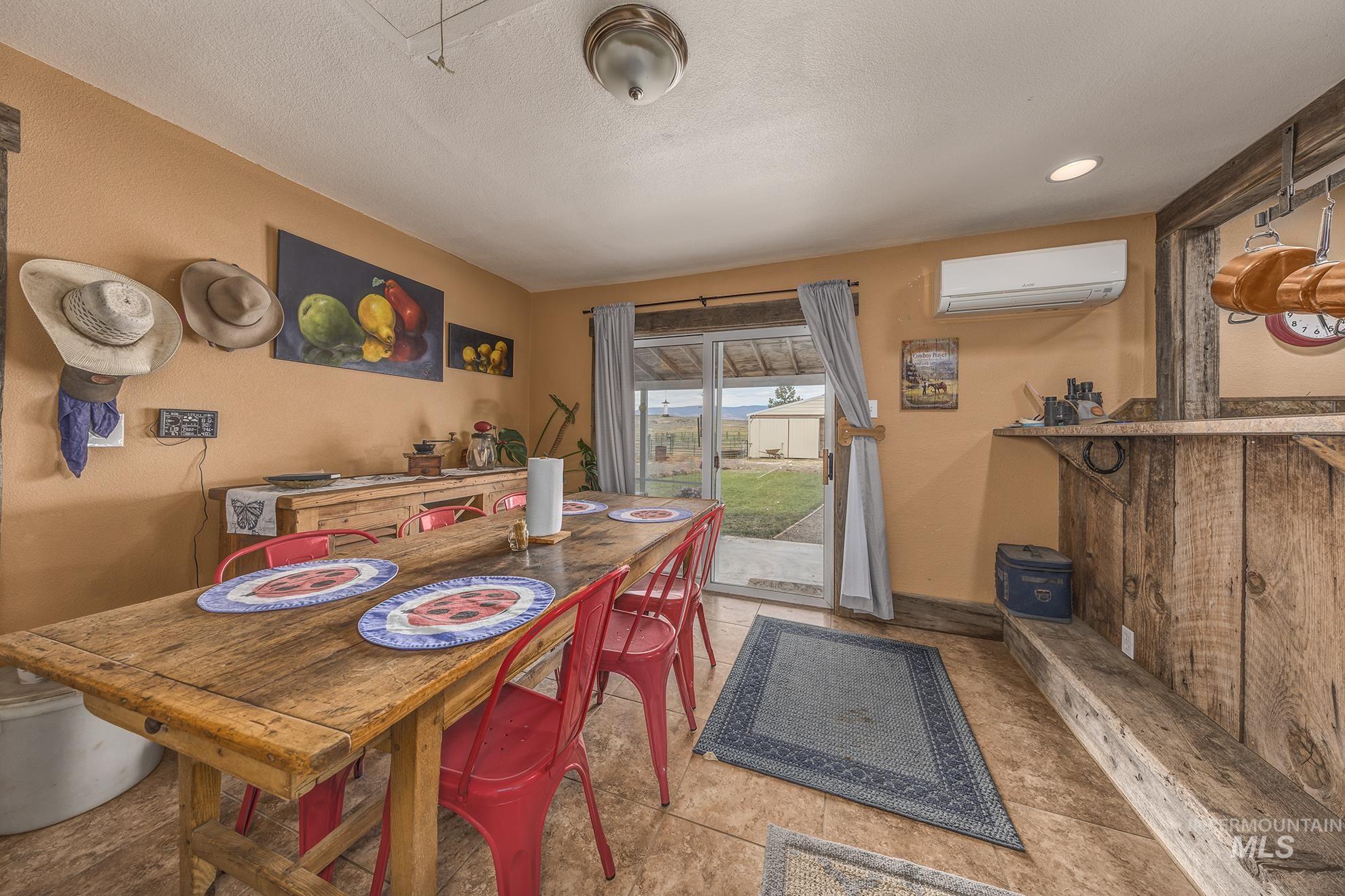 Dining room with an AC wall unit, tile patterned floors, and a textured ceiling