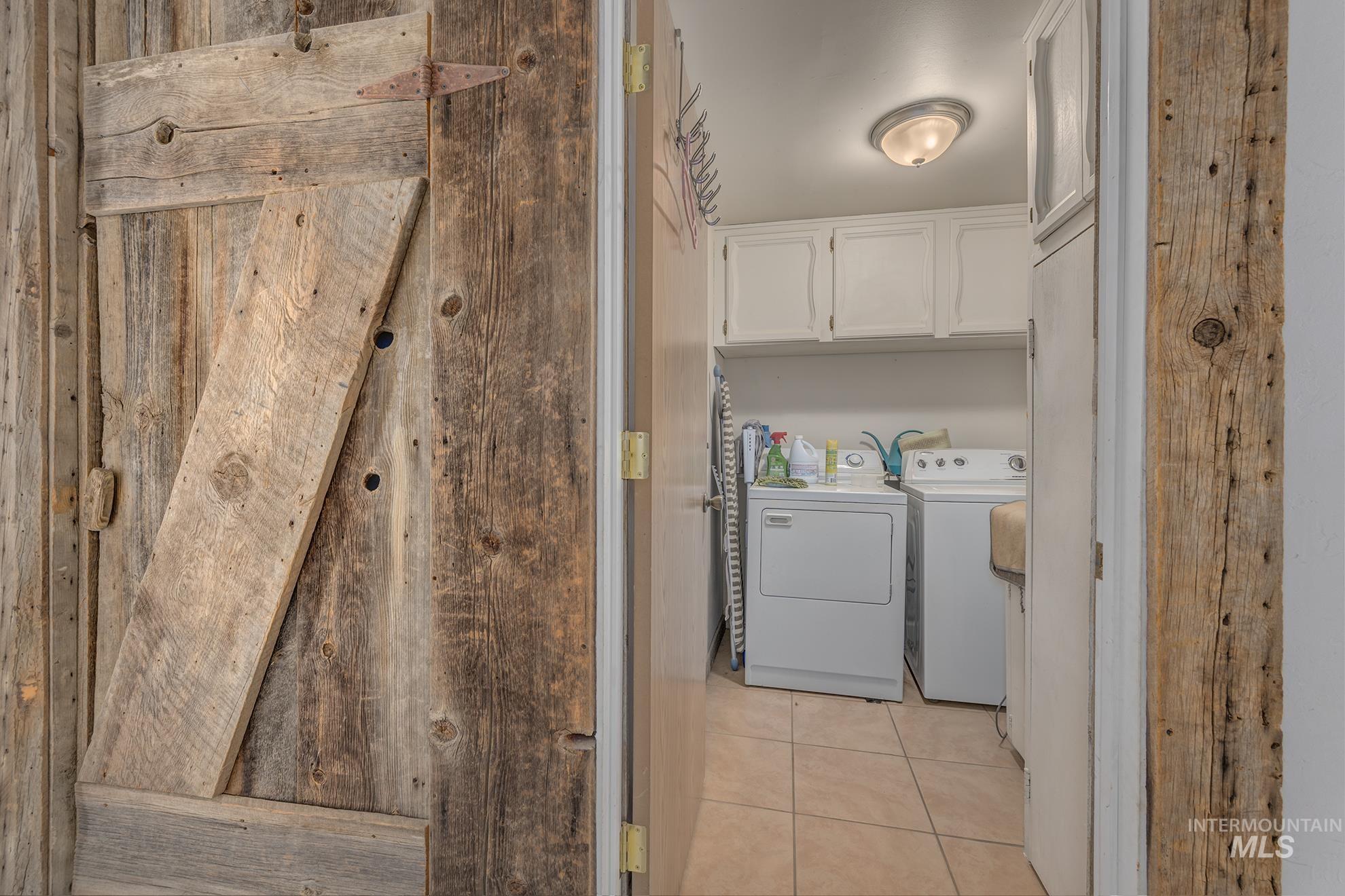 Laundry room featuring washer and clothes dryer, light tile patterned floors, and cabinet space