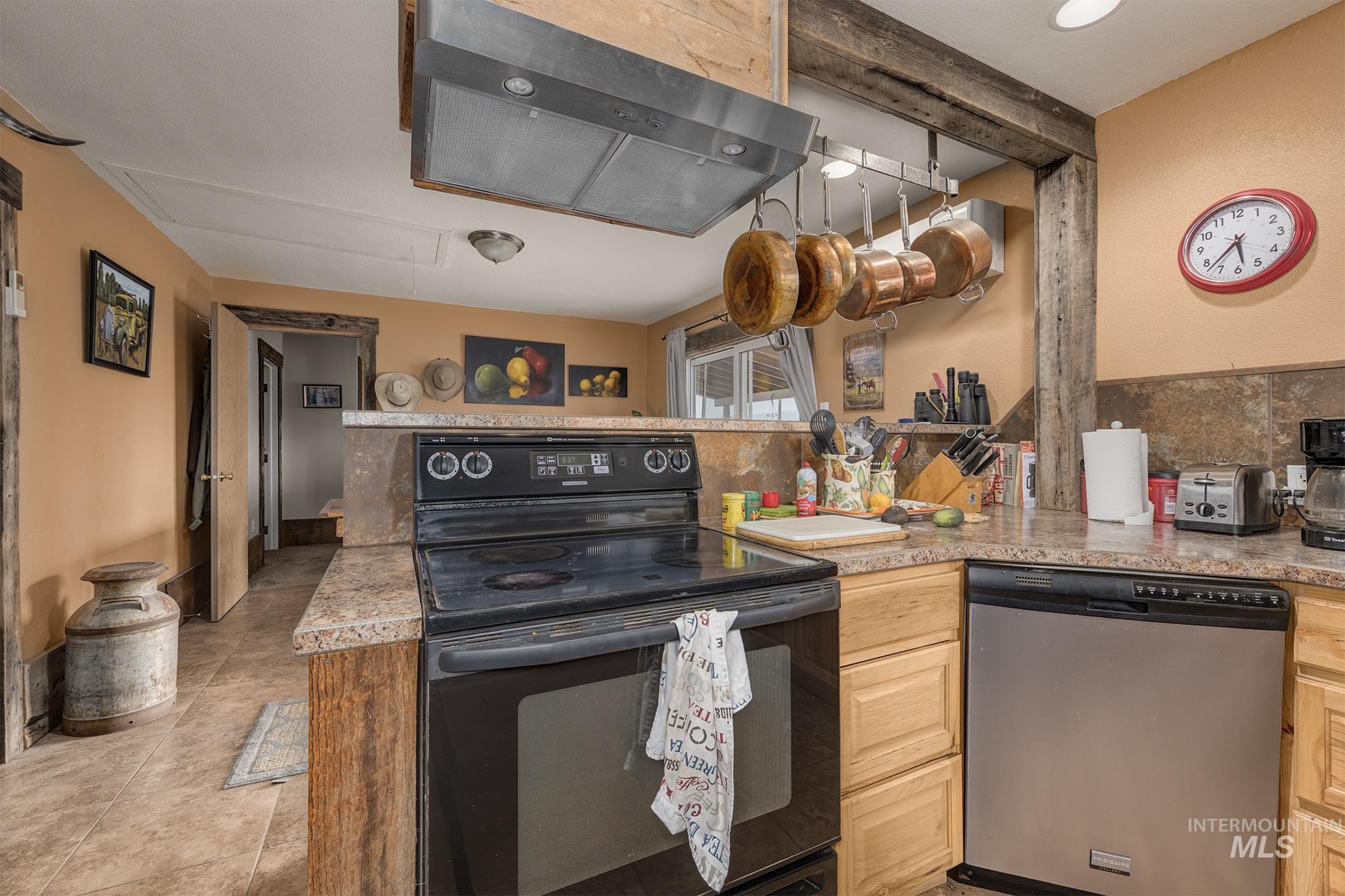 Kitchen featuring black electric range, ventilation hood, dishwasher, and light countertops