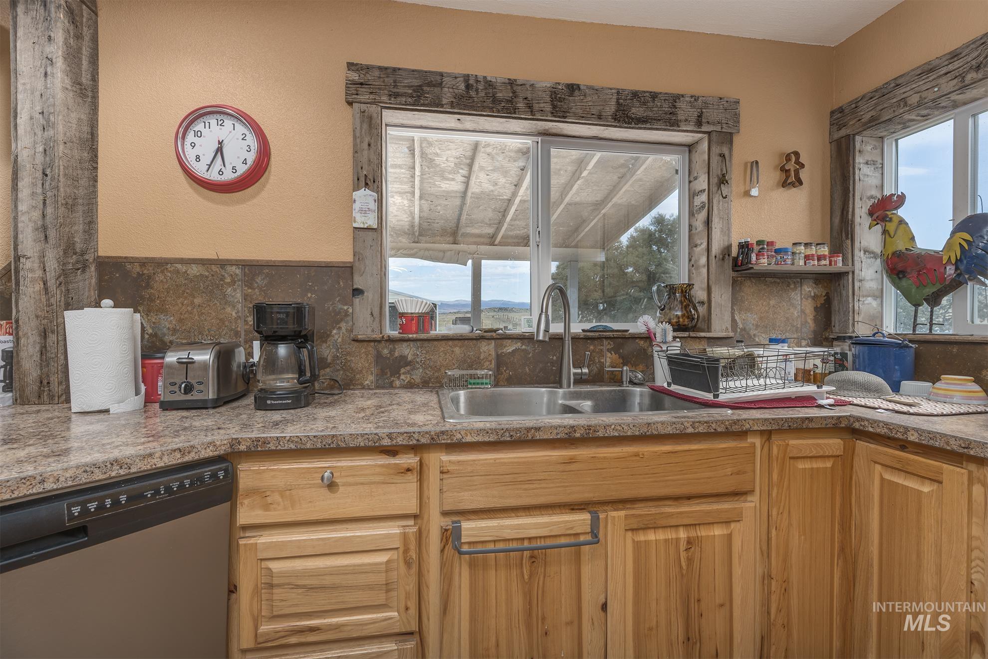Kitchen featuring stainless steel dishwasher, healthy amount of natural light, decorative backsplash, and a textured wall