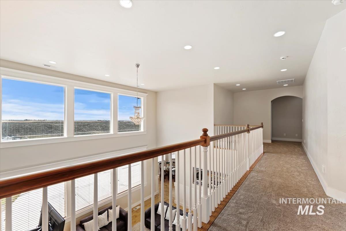 Corridor featuring arched walkways, light colored carpet, and recessed lighting