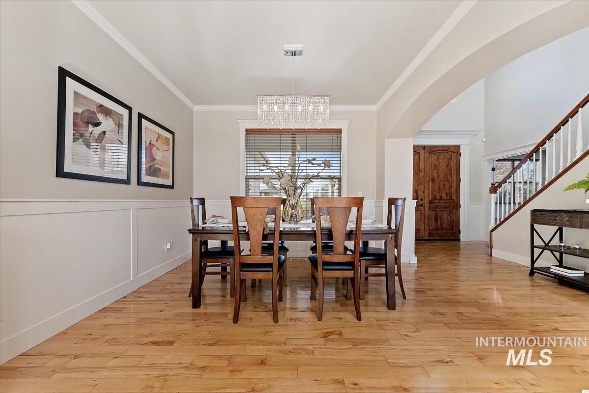 Dining room featuring crown molding, light wood-style floors, stairs, and a chandelier