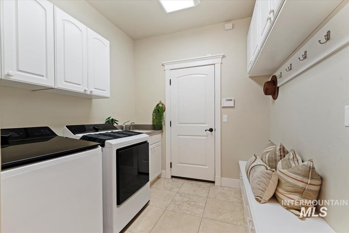 Laundry area with cabinet space, light tile patterned flooring, and separate washer and dryer