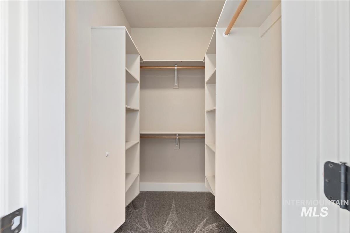Walk in closet featuring dark colored carpet