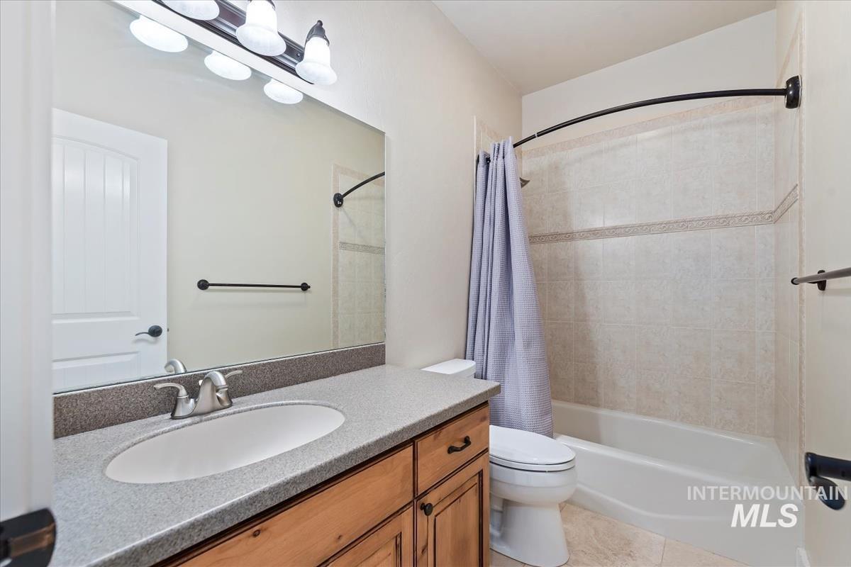 Full bathroom featuring shower / bathtub combination with curtain, vanity, and light tile patterned floors