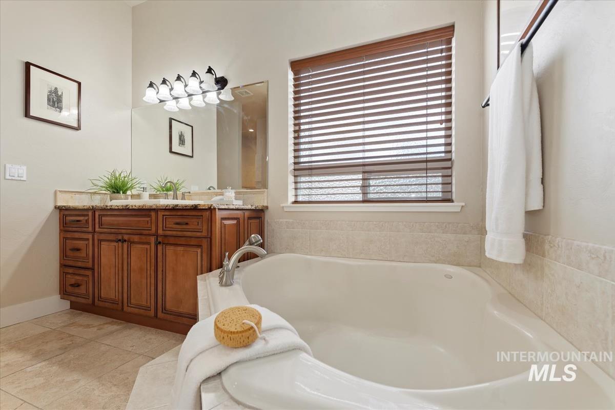Bathroom with vanity, a bath, and light tile patterned flooring