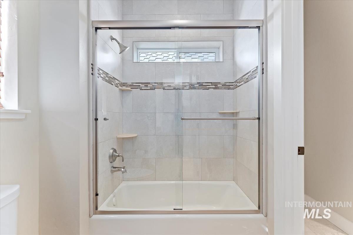 Full bath with shower / bath combination with glass door and toilet