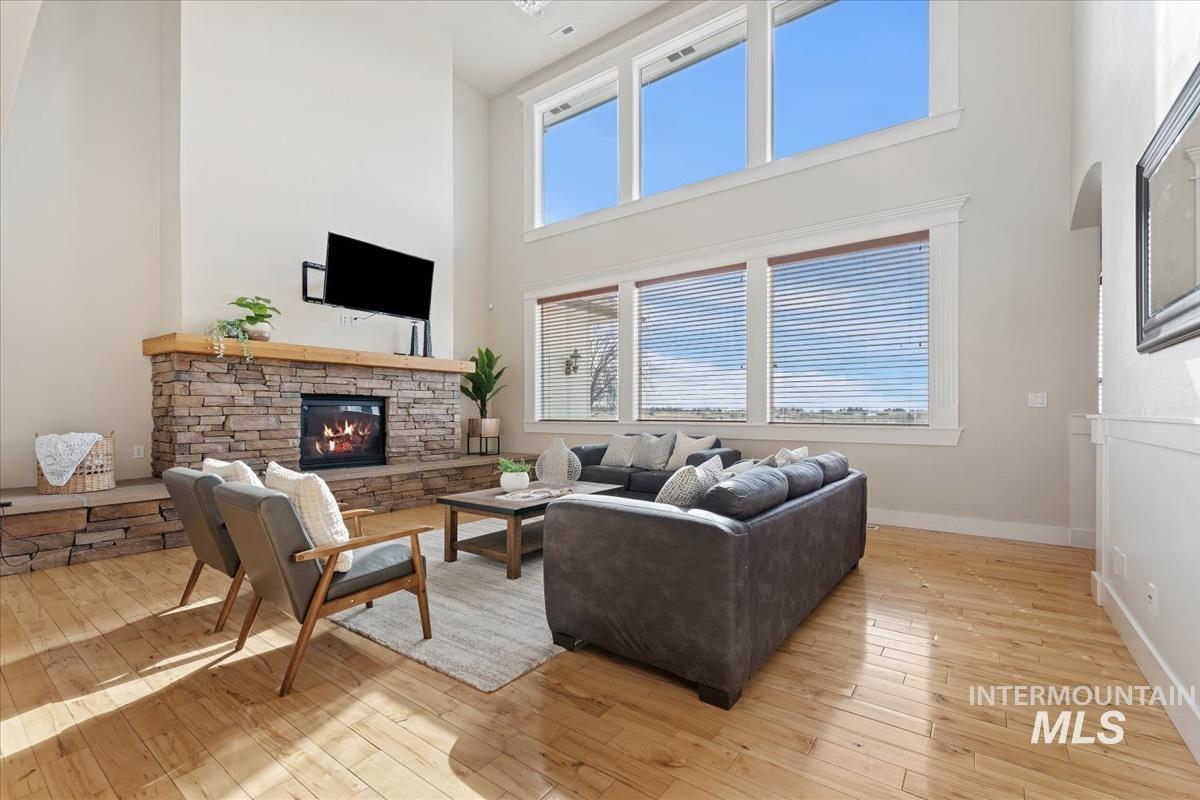 Living area featuring a fireplace, a towering ceiling, and light wood finished floors