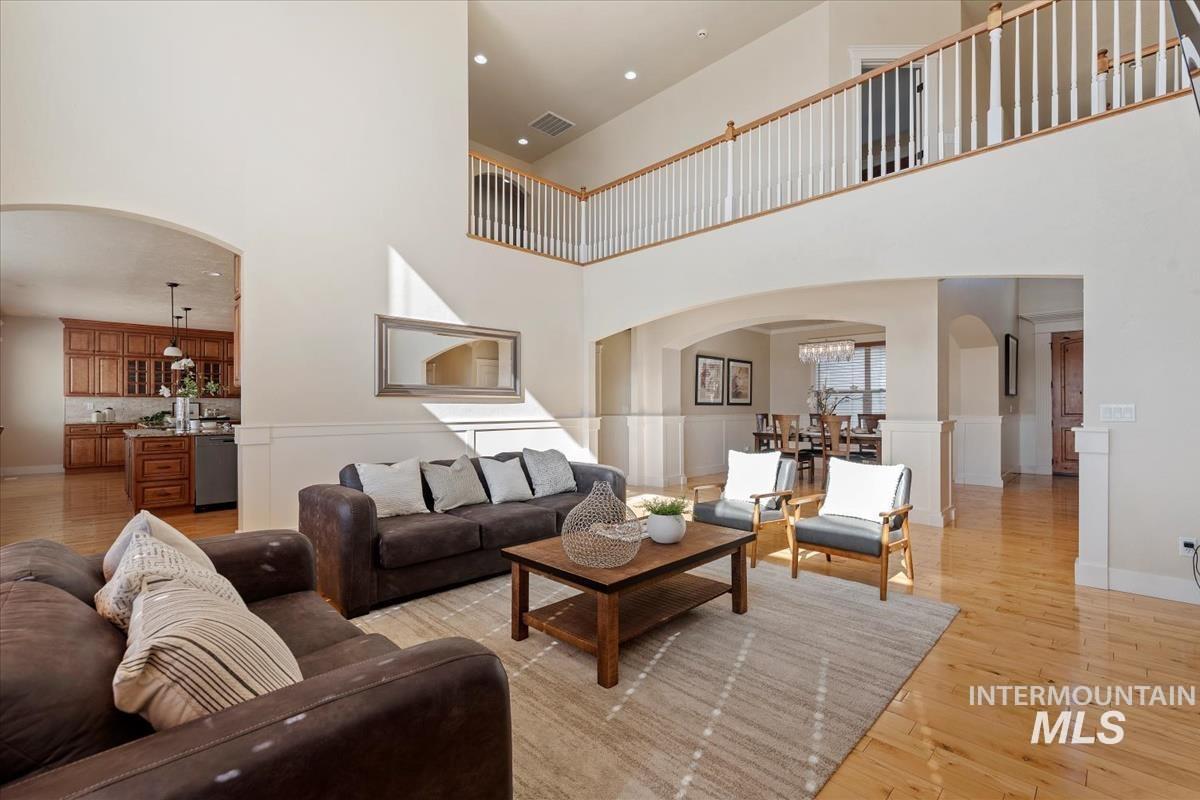 Living area with arched walkways, light wood finished floors, a high ceiling, and a chandelier