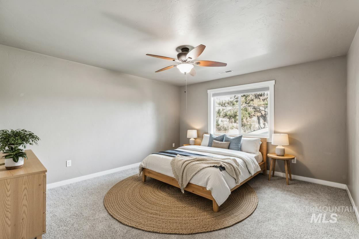Carpeted bedroom featuring a ceiling fan and baseboards