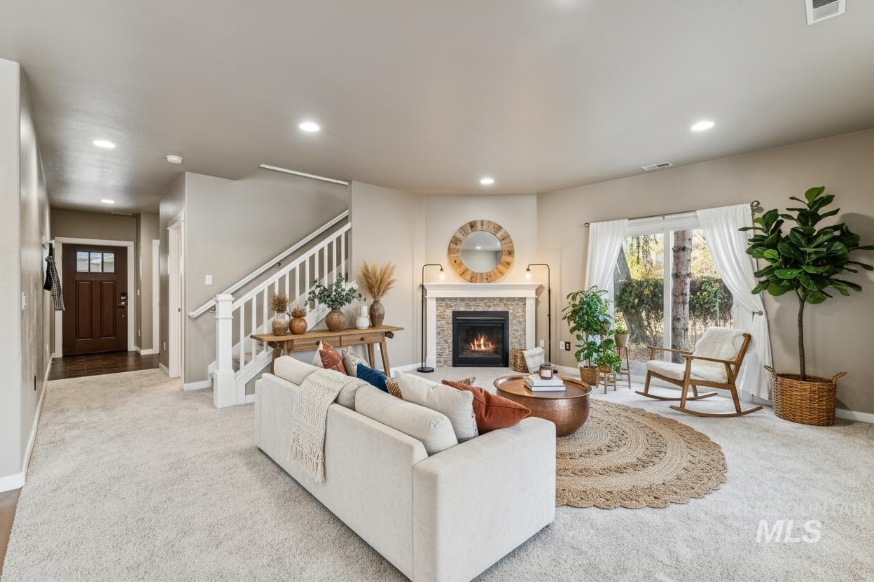 Carpeted living area with recessed lighting, stairs, and a lit fireplace