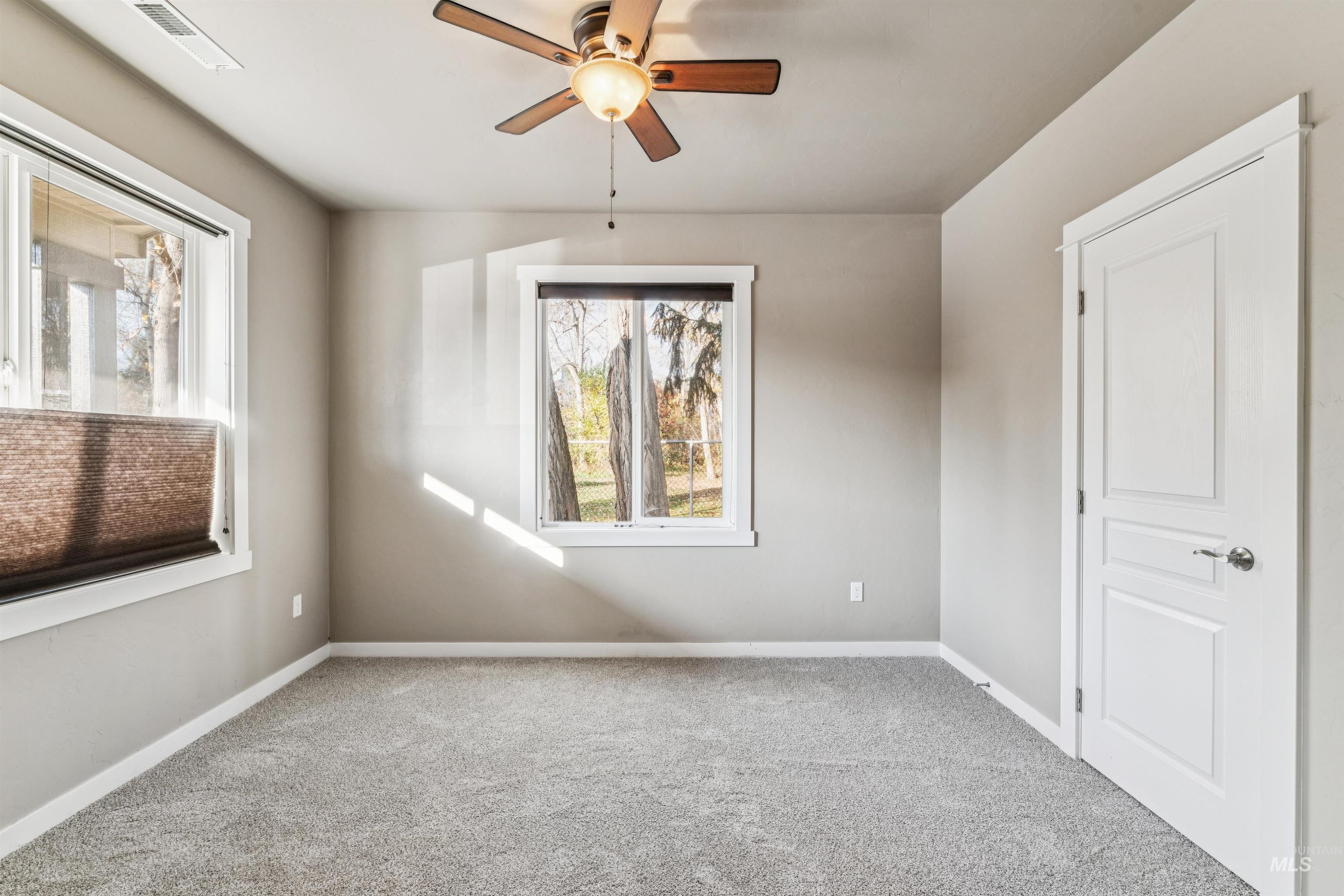 Carpeted spare room featuring baseboards and ceiling fan