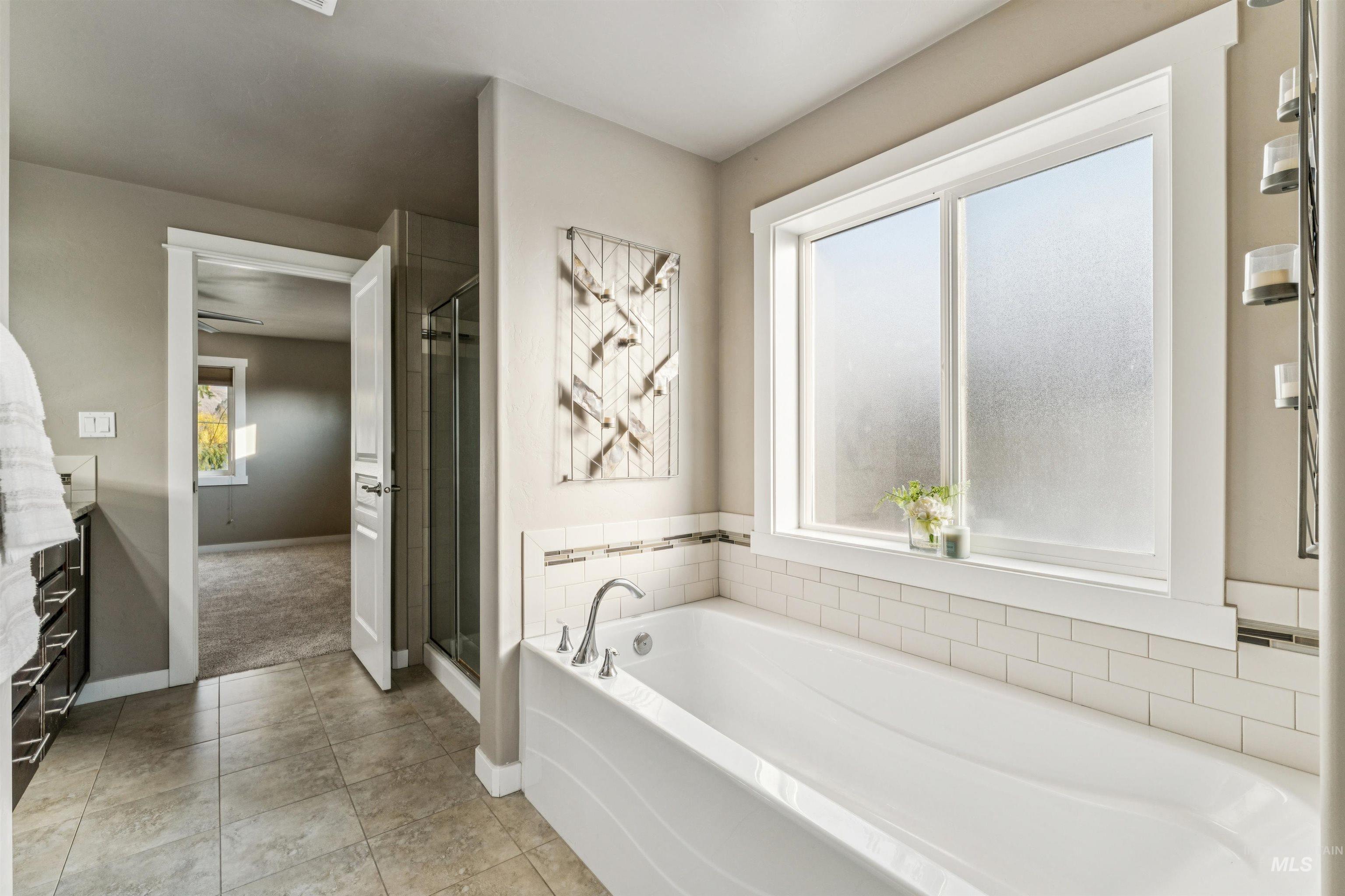 Bathroom with a bath, light tile patterned flooring, a shower stall, and vanity