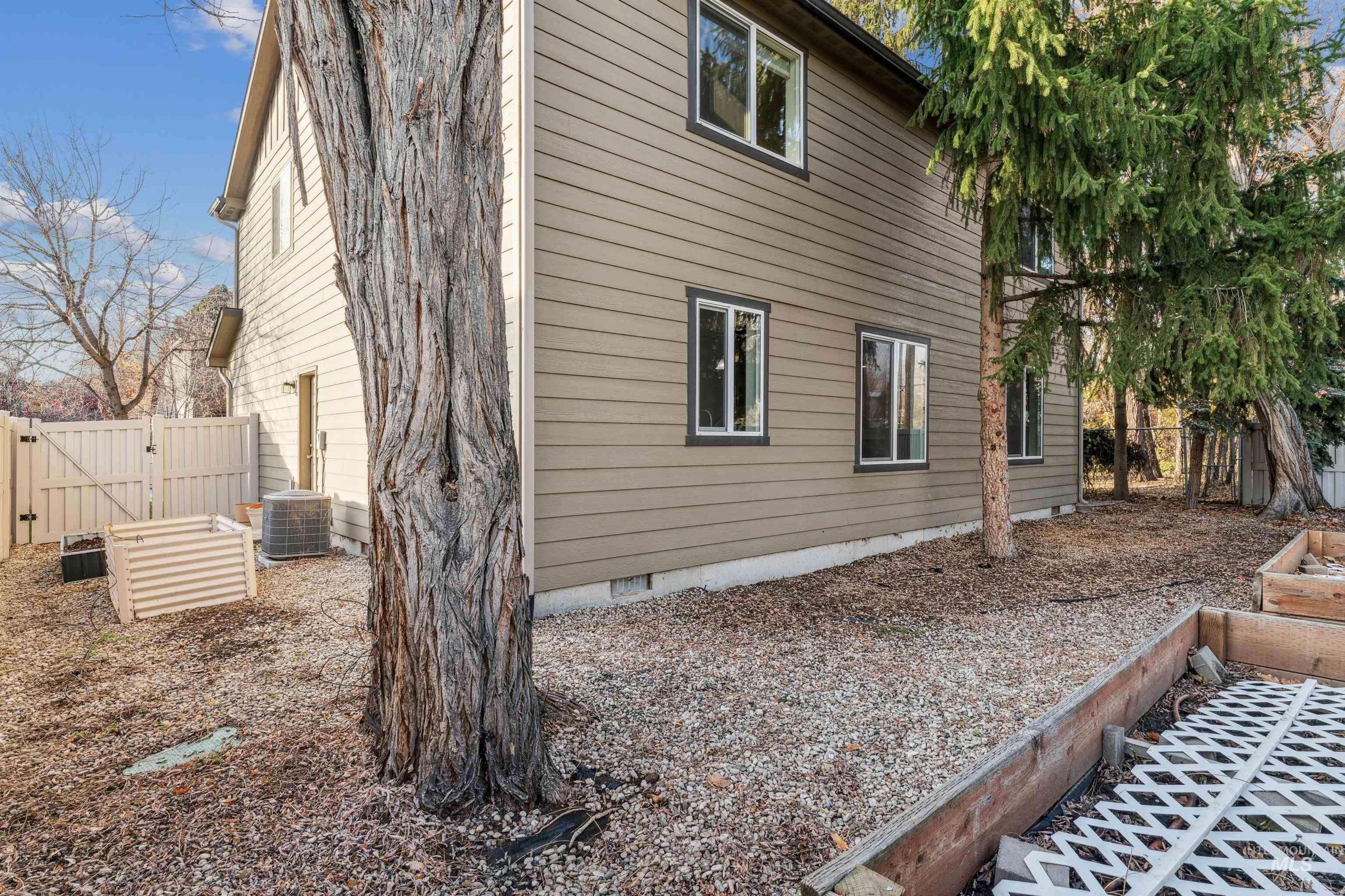 View of home's exterior featuring crawl space, a gate, and a vegetable garden