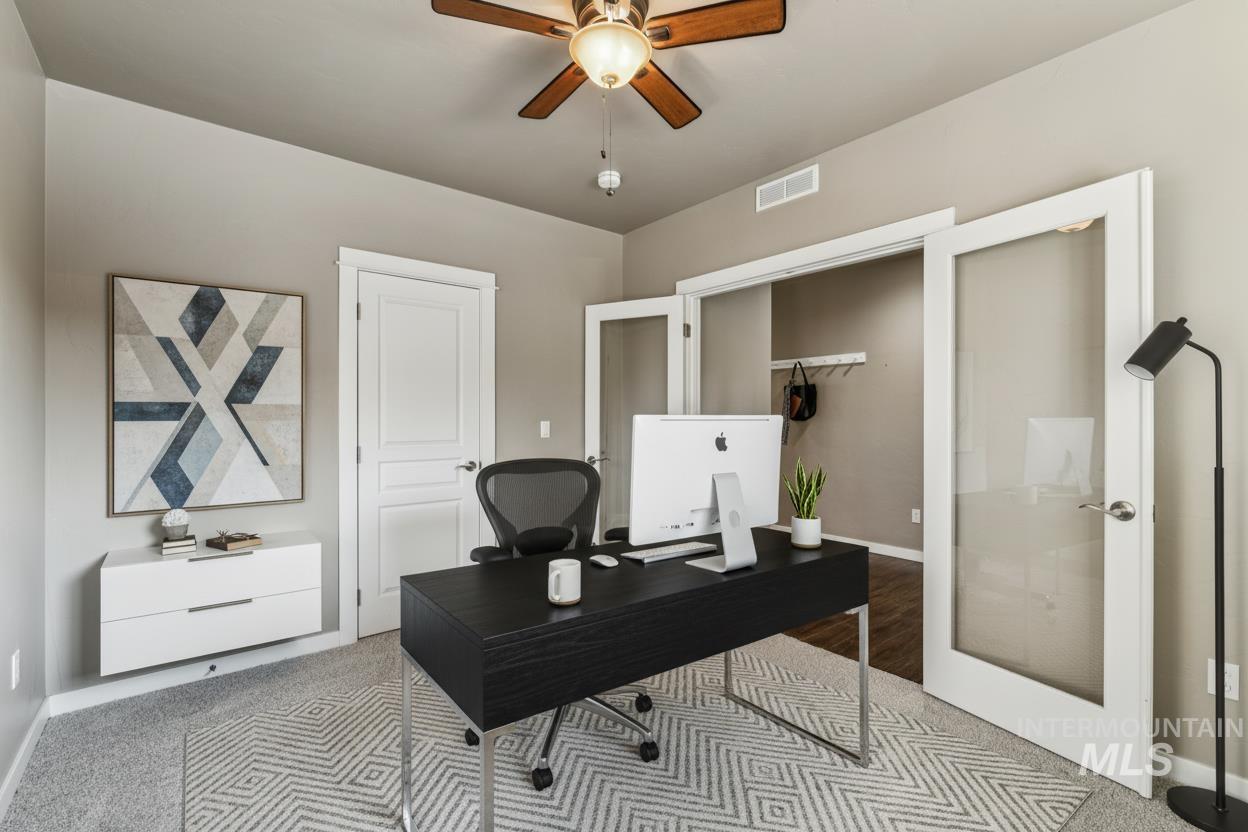 Carpeted office with french doors and ceiling fan