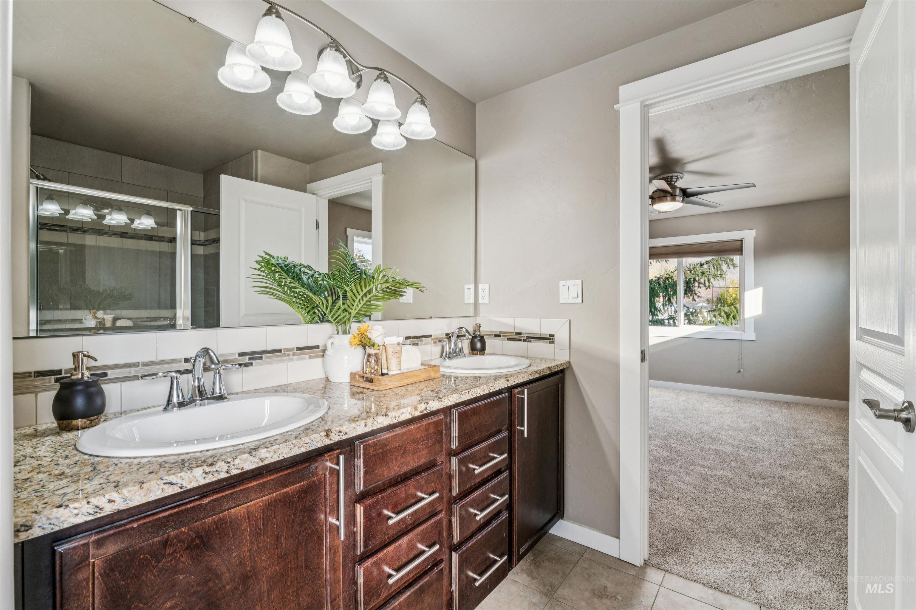 Bathroom featuring double vanity, a stall shower, light tile patterned floors, tasteful backsplash, and light carpet