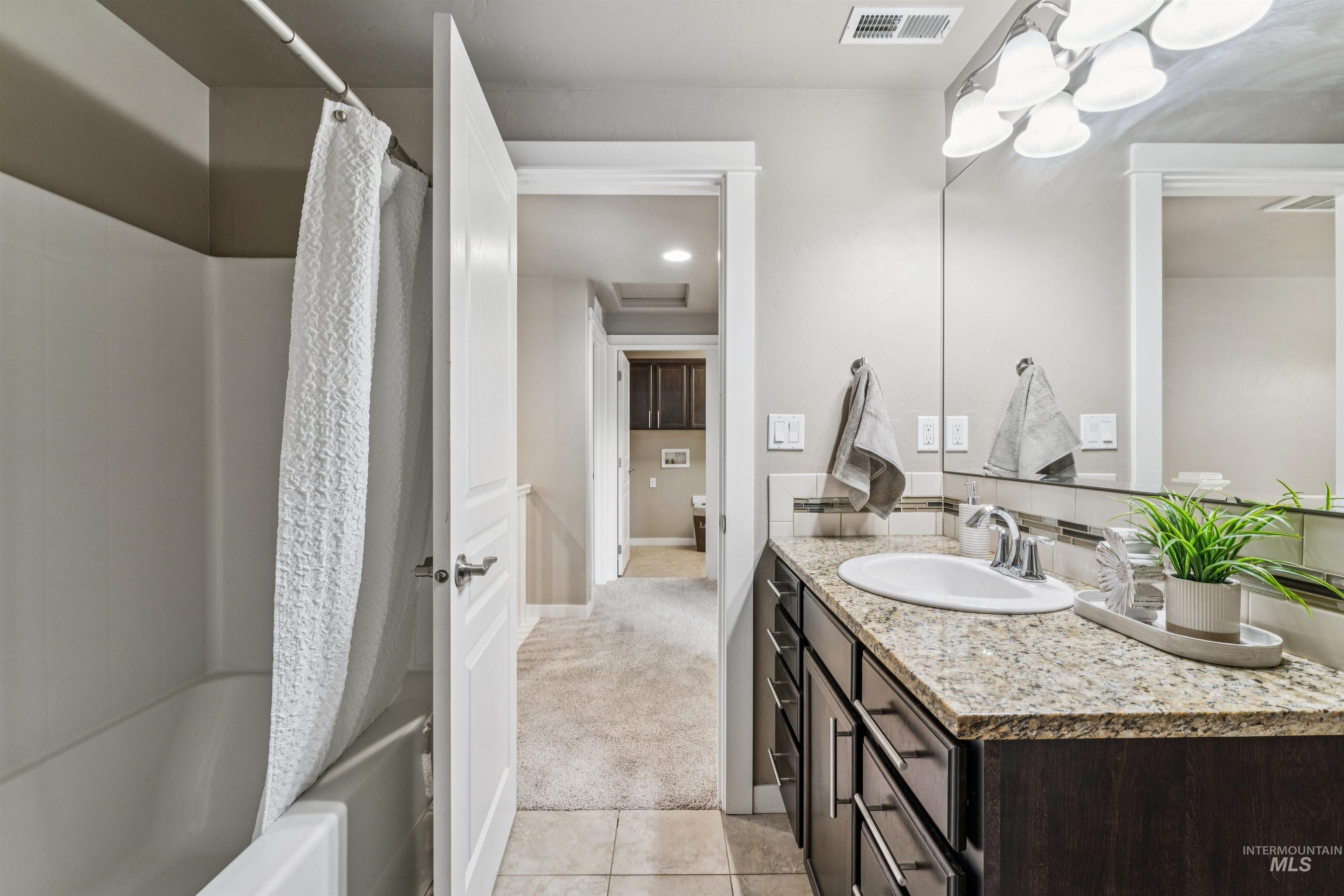 Bathroom featuring vanity, light tile patterned floors, light carpet, and shower / bath combo with shower curtain