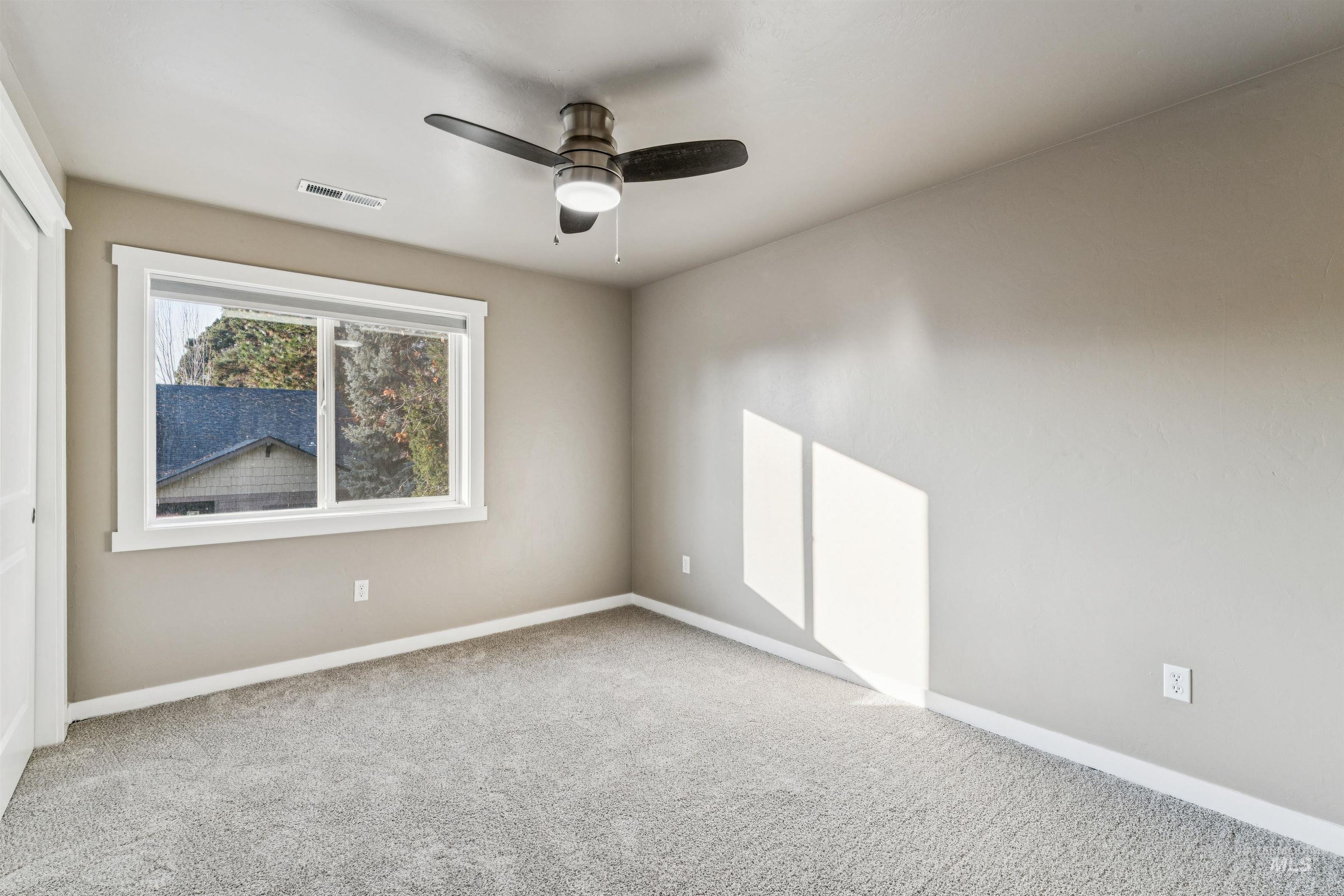 Carpeted empty room featuring baseboards and a ceiling fan