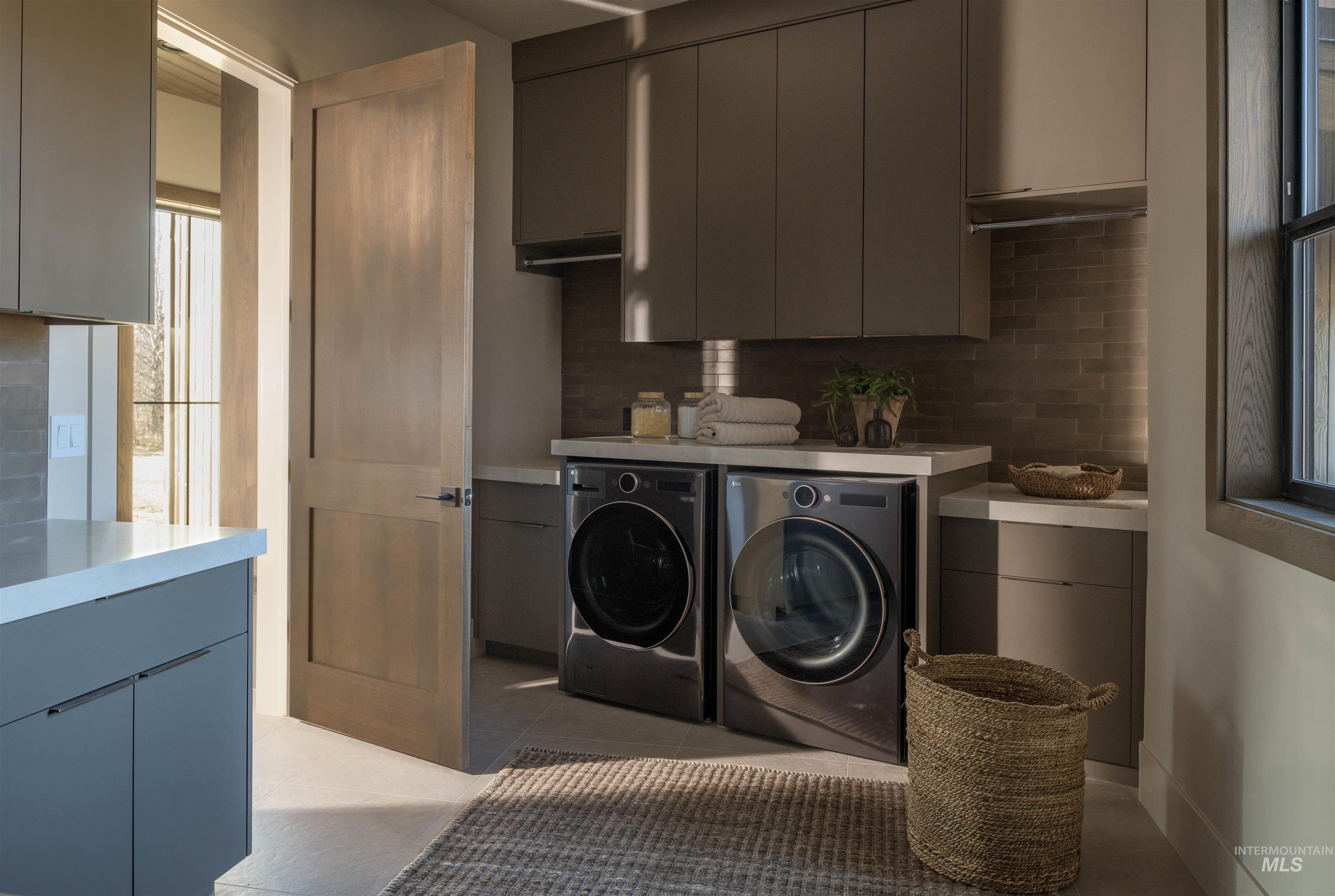 Laundry area with washer and dryer, light tile patterned floors, and cabinet space