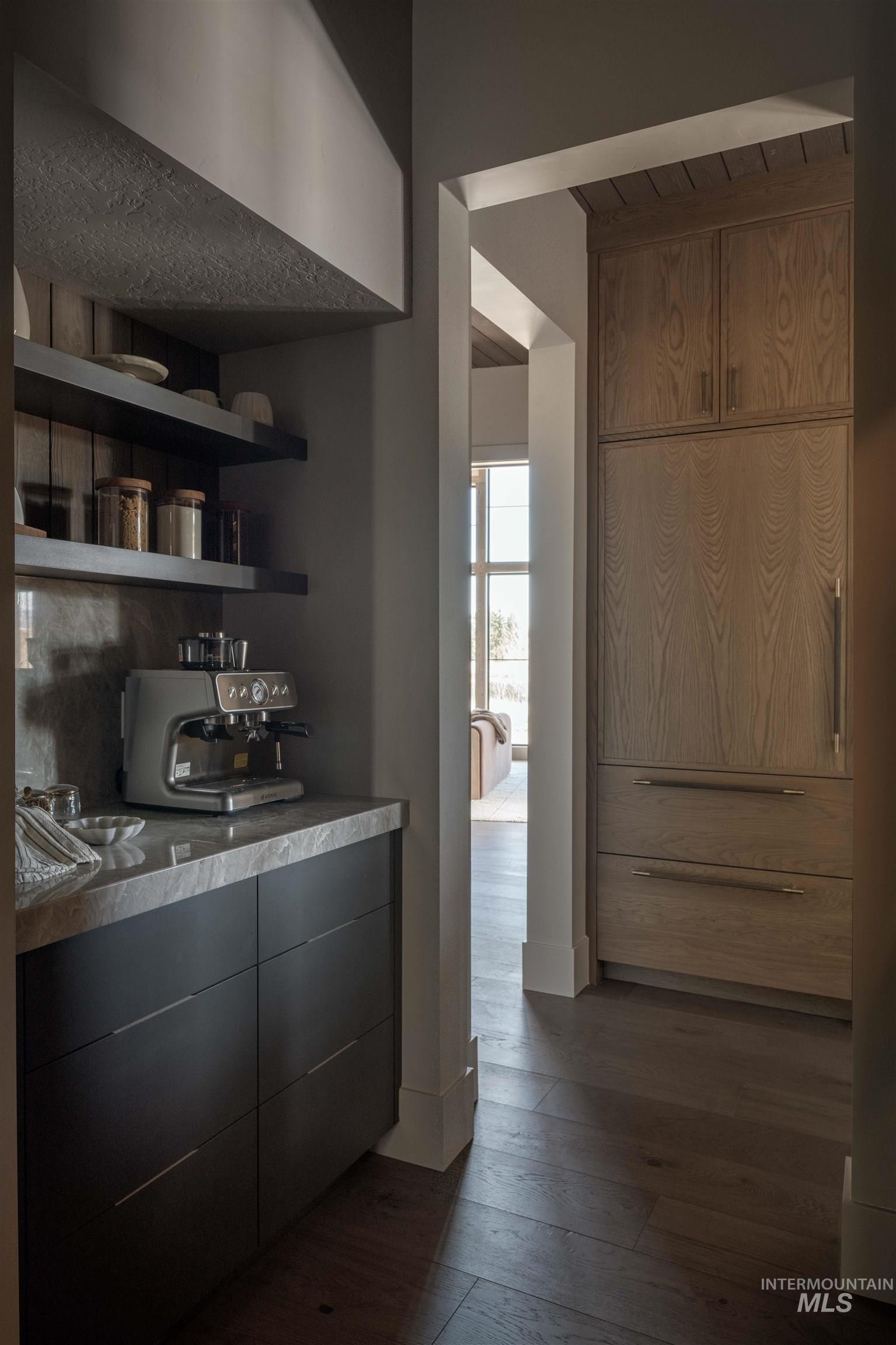 Pantry featuring dark wood-style floors, modern cabinets, light countertops, and open shelves