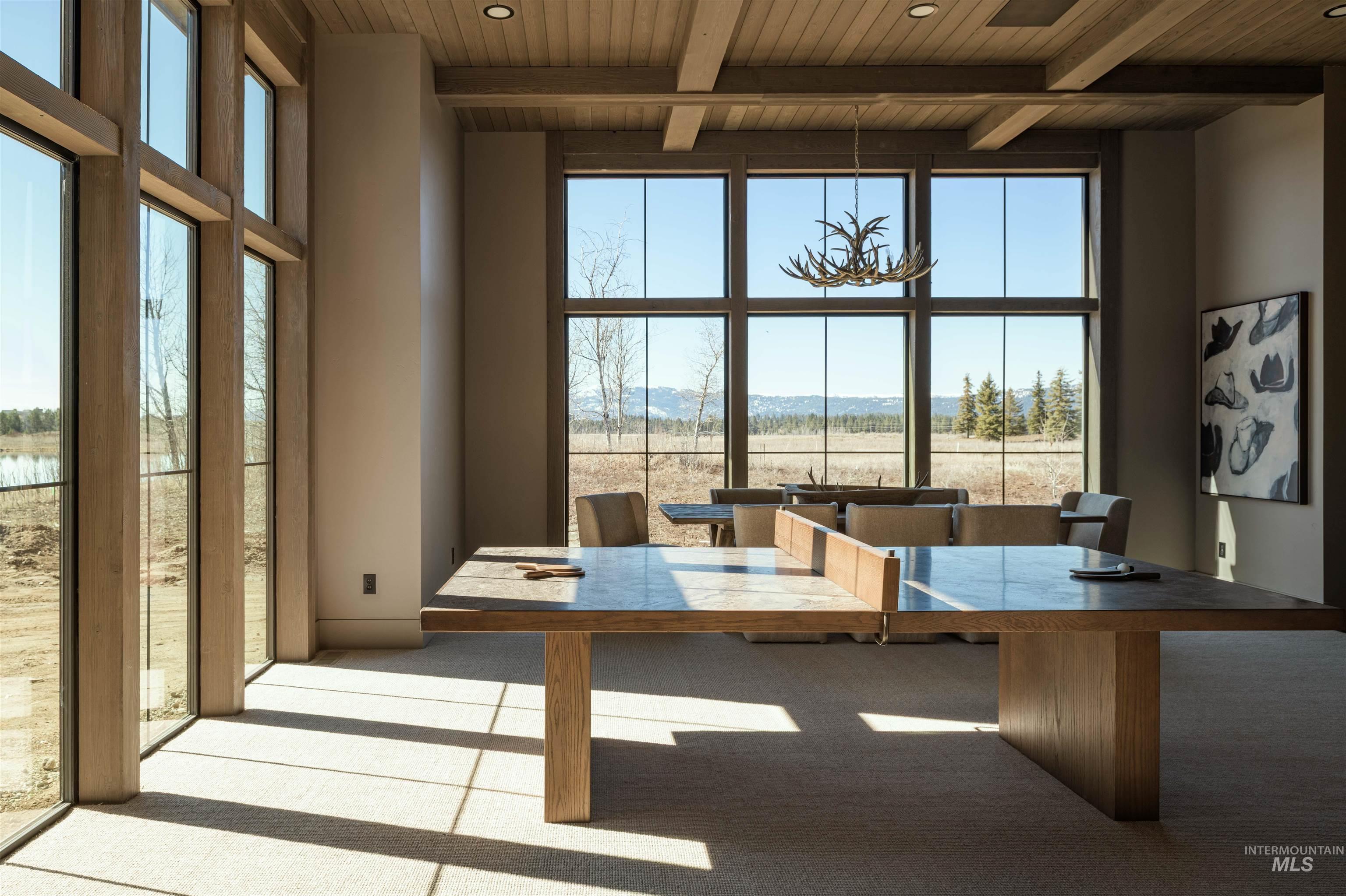 Bonus Room with light colored carpet, expansive windows, a high wooden beamed ceiling, and hanging lights. Table for playing games, ping pong table and 115" Smart TV with Surround sound.