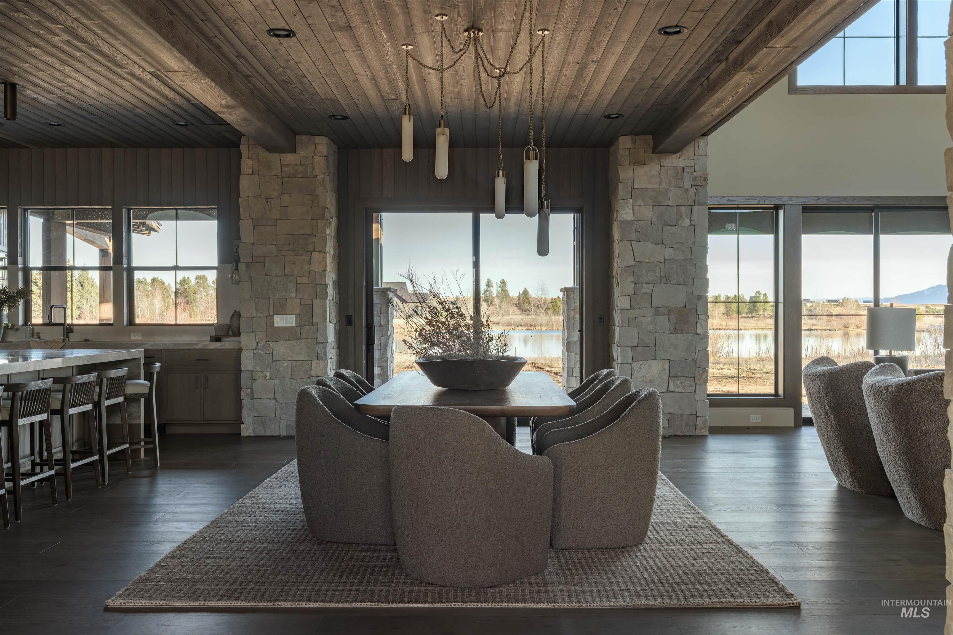 Dining space with dark wood finished floors, a water view, and a wood ceiling with exposed beams