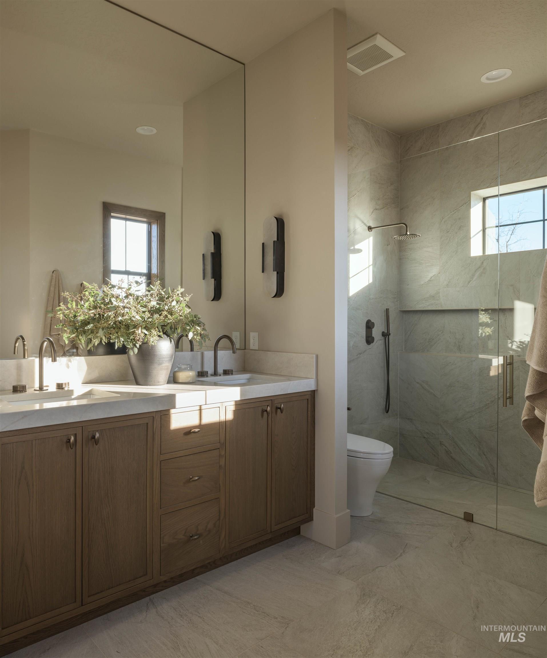 Full bathroom featuring a marble finish shower and double vanity
