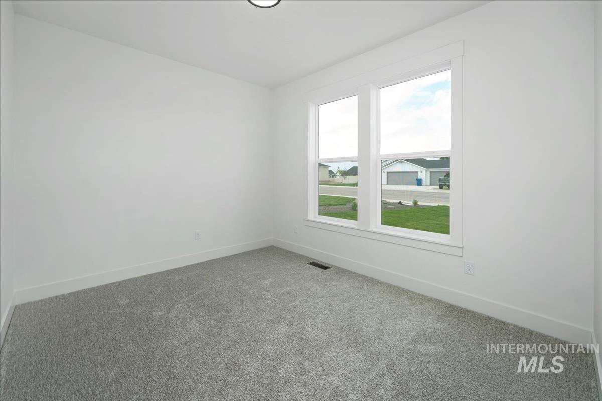 Carpeted spare room featuring baseboards