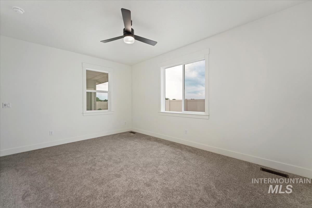 Carpeted spare room with baseboards and a ceiling fan
