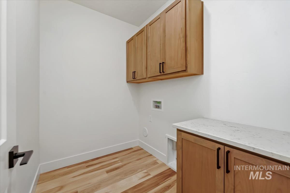 Washroom featuring cabinet space, hookup for a washing machine, light wood-style flooring, and gas dryer hookup