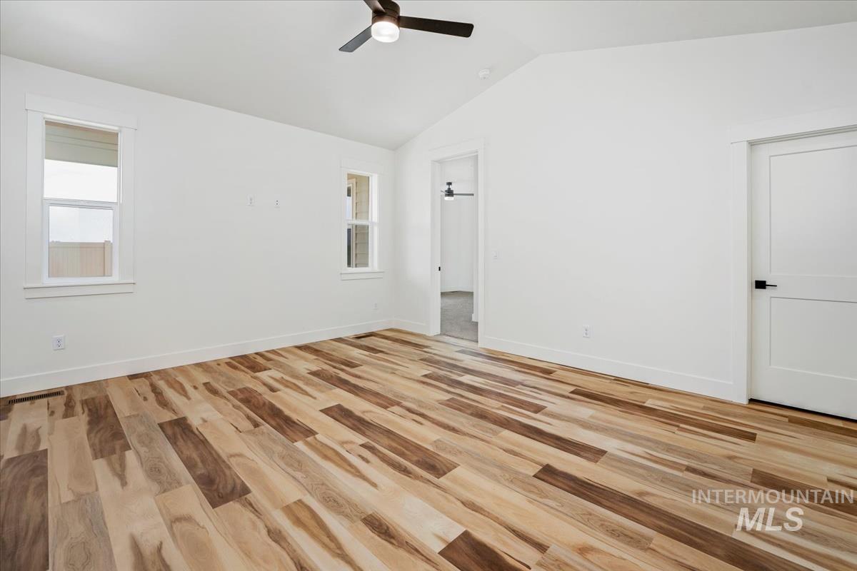 Unfurnished room featuring vaulted ceiling, light wood-style flooring, and a ceiling fan