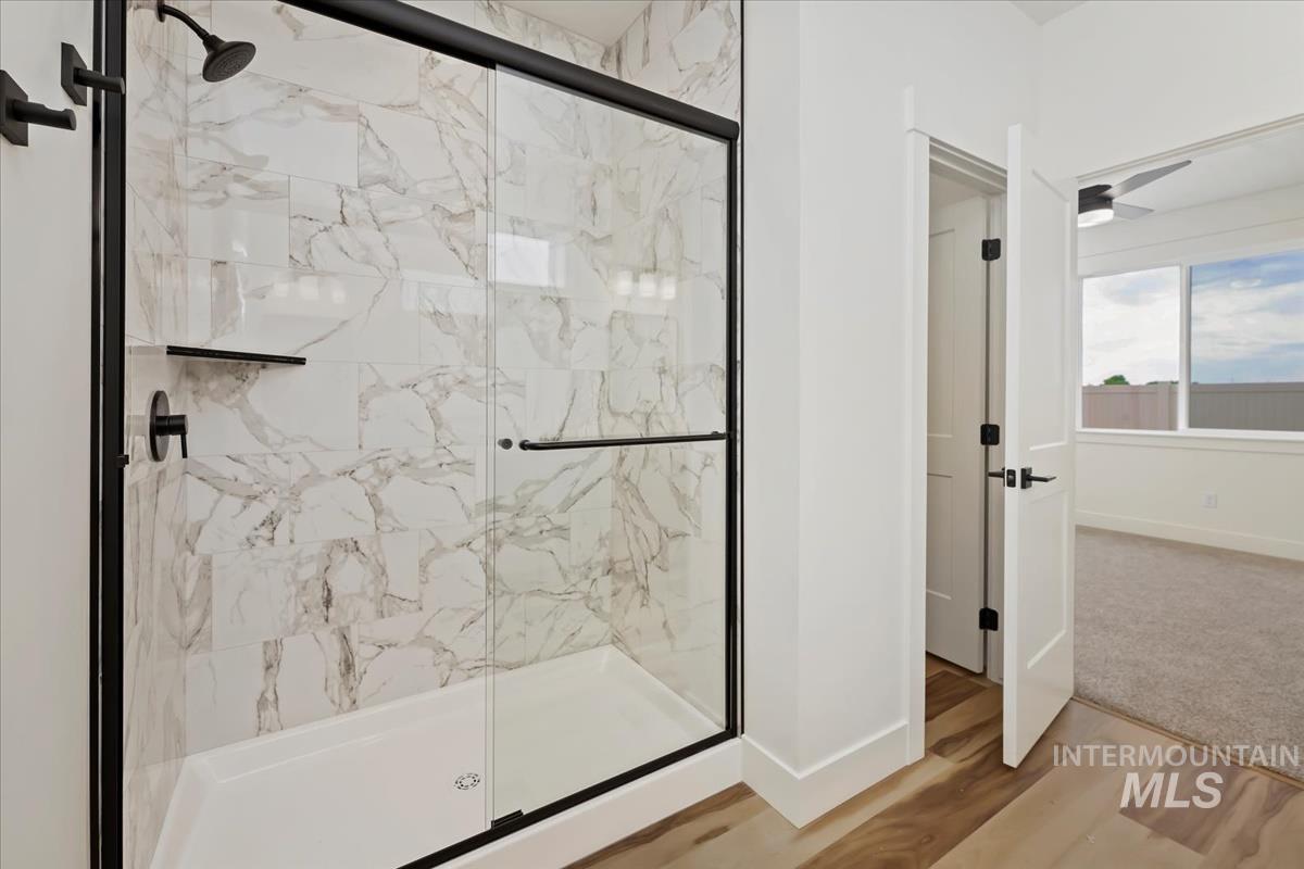 Bathroom featuring a marble finish shower and wood finished floors