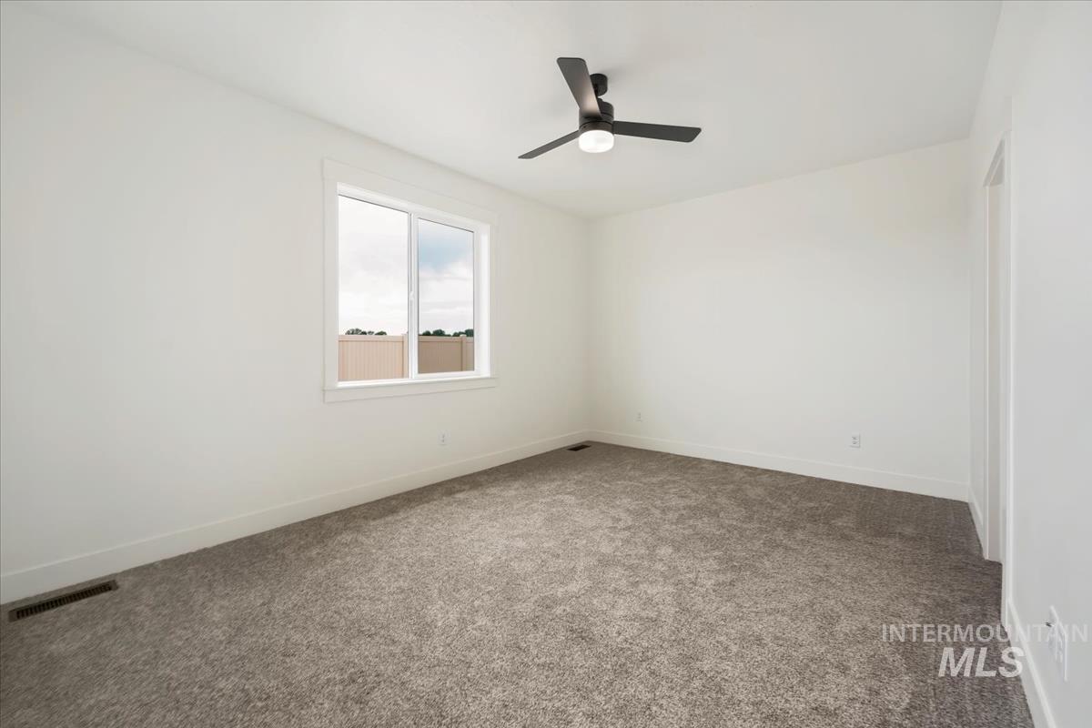 Empty room with dark carpet and a ceiling fan