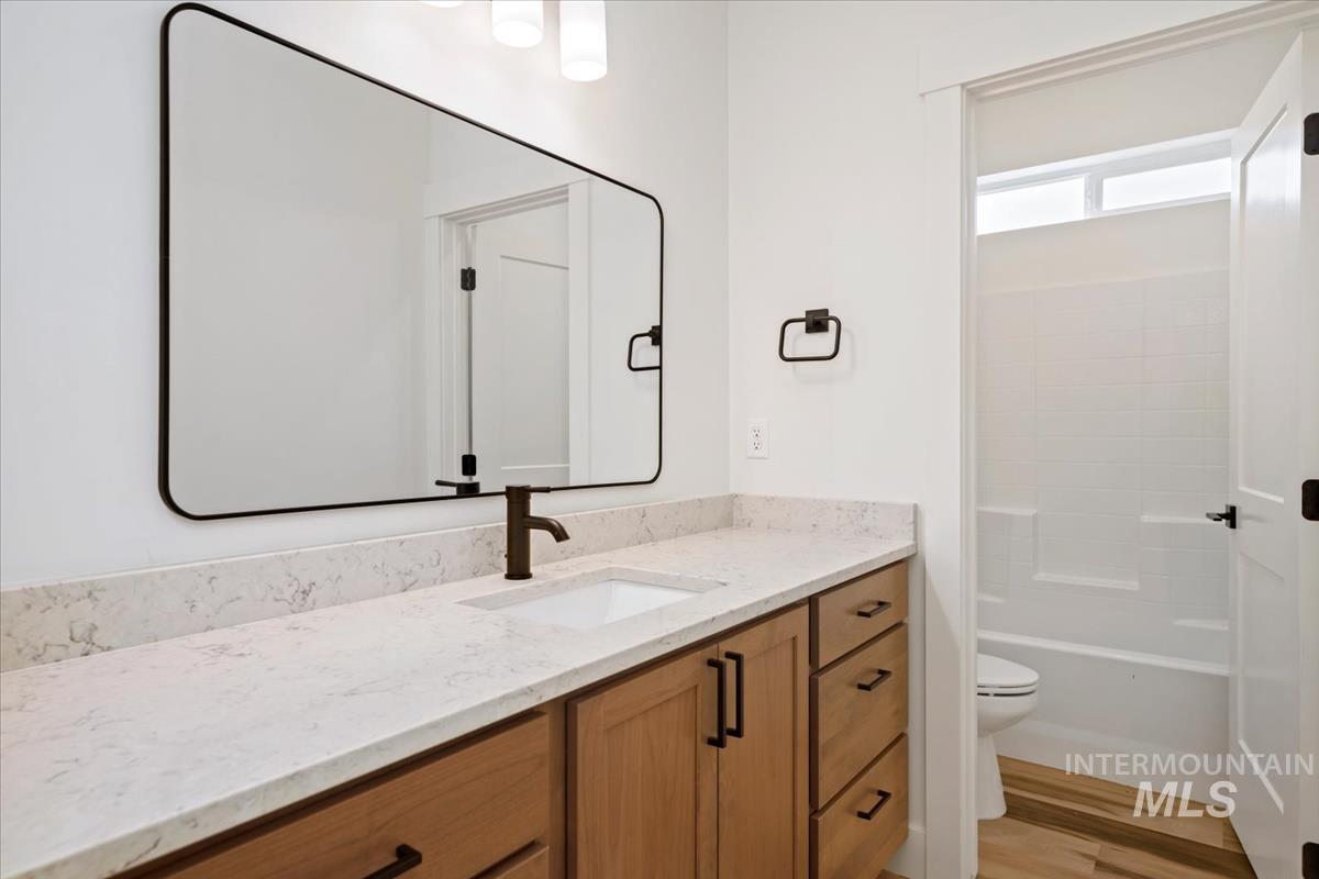 Full bathroom with vanity, shower / bath combination, and wood finished floors