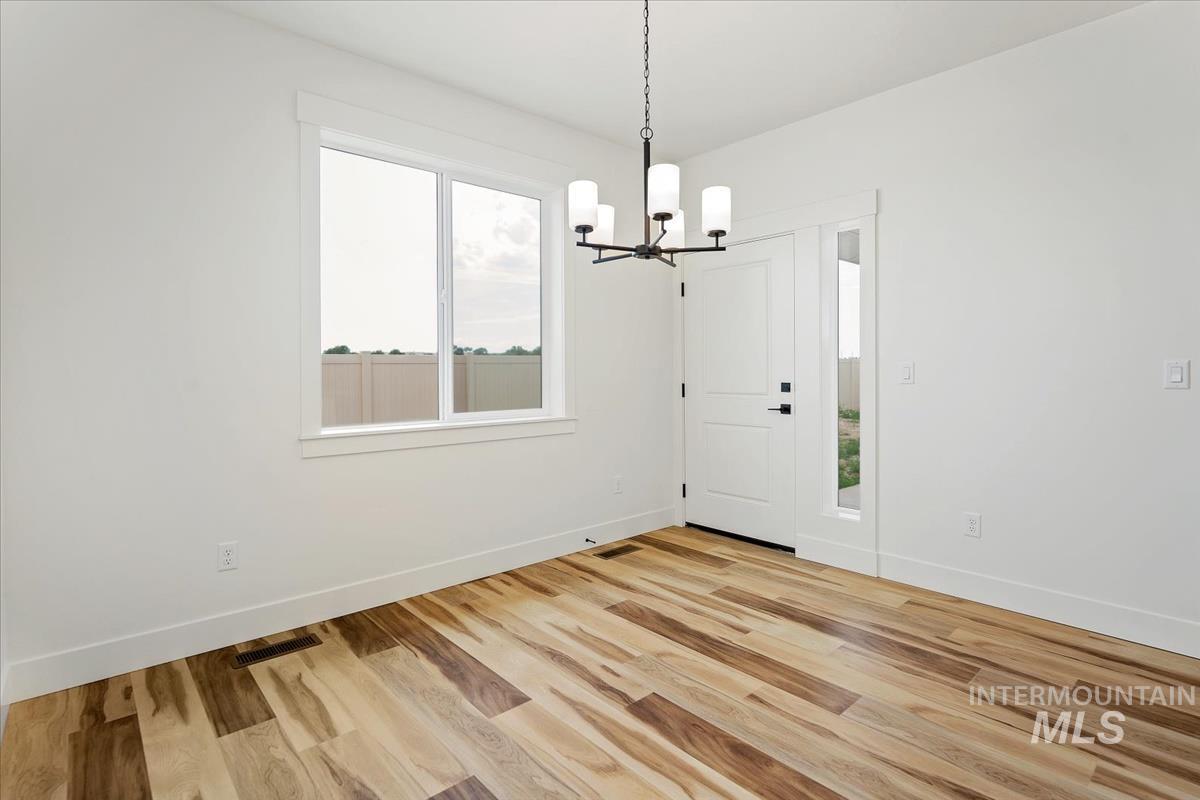 Unfurnished dining area with a chandelier and light wood-style floors