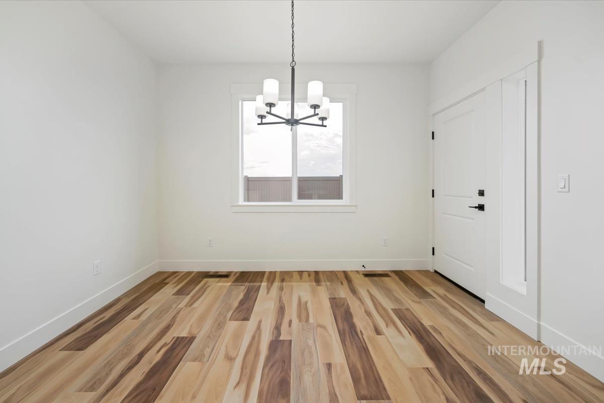 Unfurnished dining area with a chandelier and light wood-type flooring