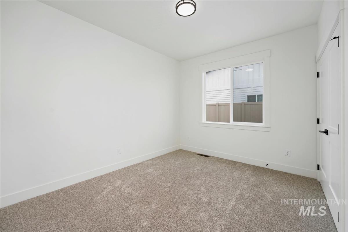 Empty room featuring light colored carpet and baseboards